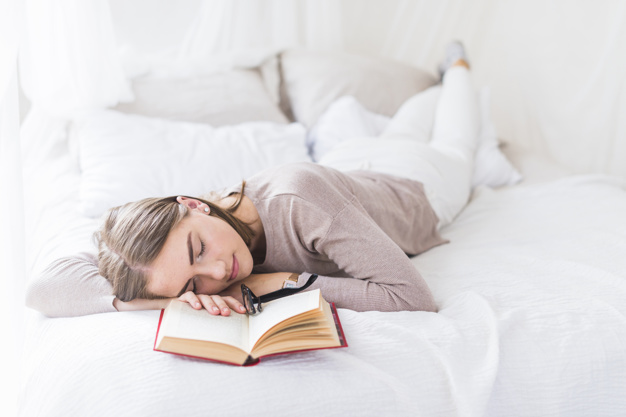 woman sleeping on bed with eyeglasses over the open book 23 2147872063 - So schützen Sie sich auf Reisen vor Malaria